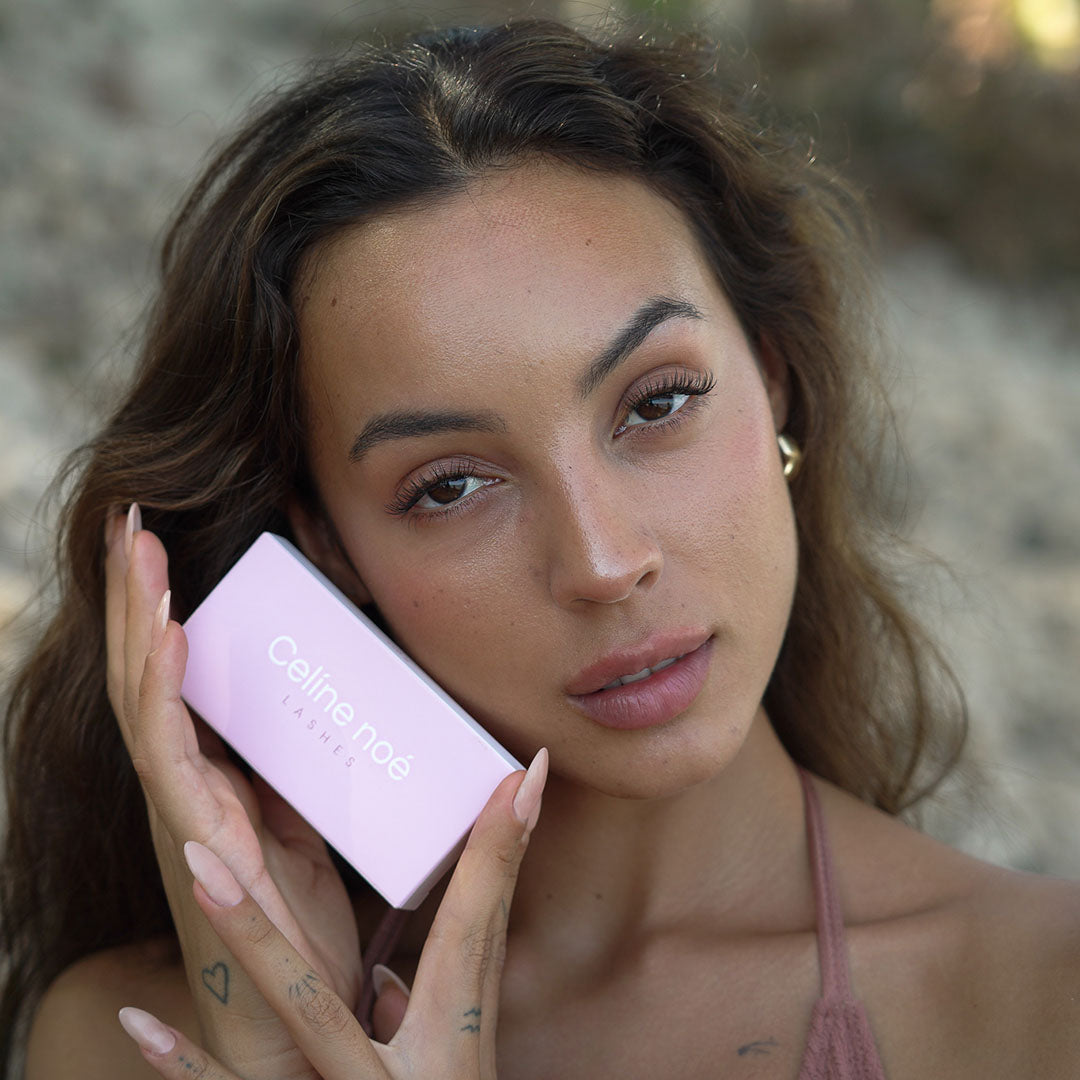 Model en zangeres Juli die de lash stijl soft focus draagt en de verpakking van Celine noe vast houd.