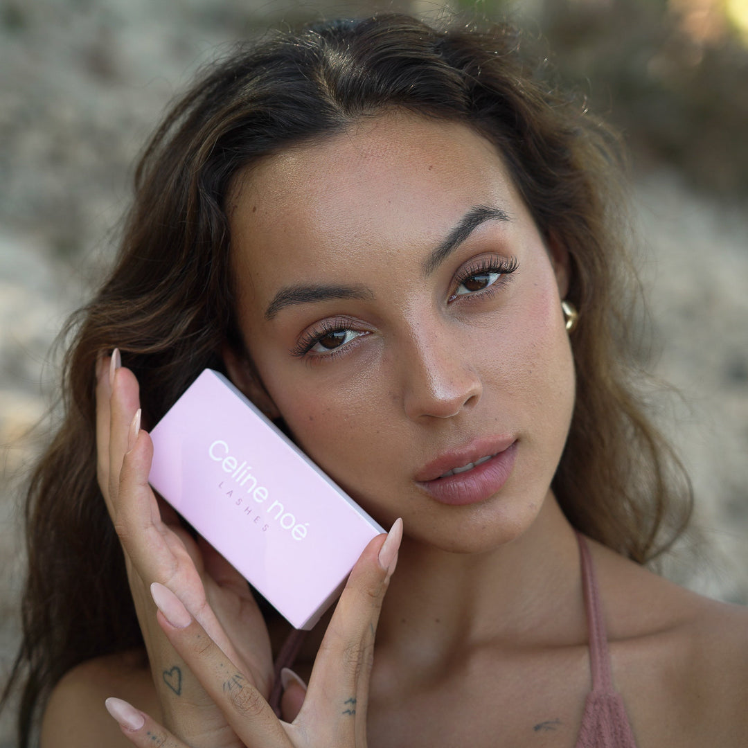 Model en zangeres Juli die de lash stijl soft focus draagt en de verpakking van Celine noe vast houd.